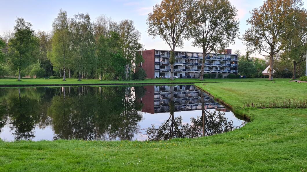 Flatgebouw bij plas water bij het Gorechtpark te Hoogezand