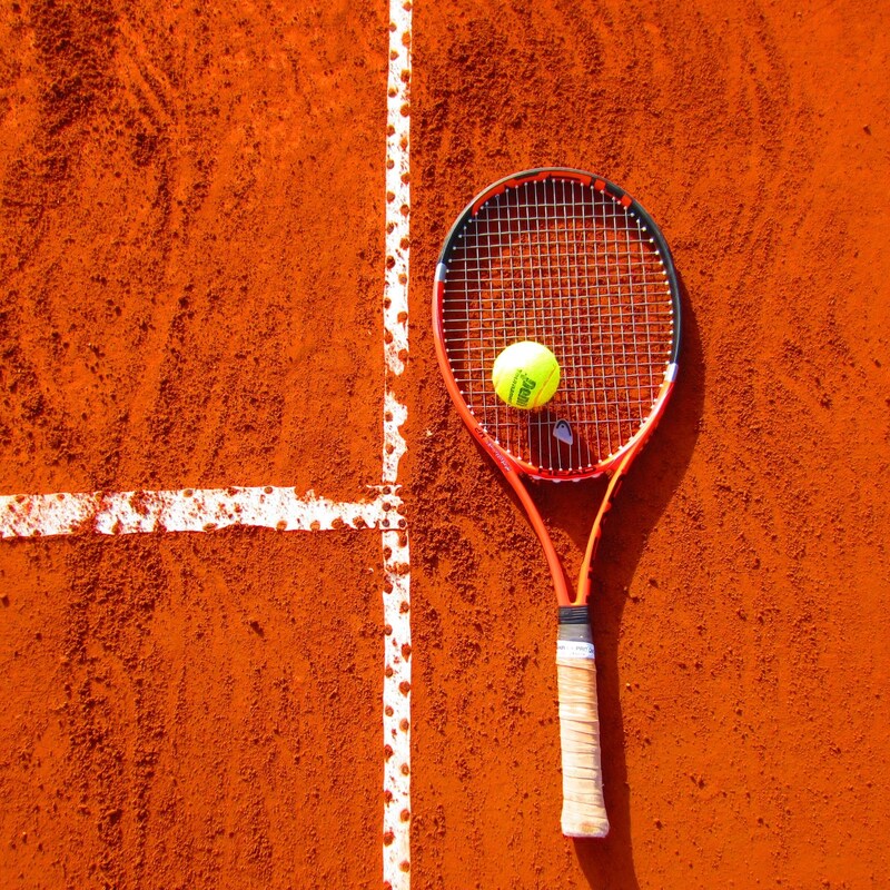 Tennisracket met tennisbal op tennisveld. 