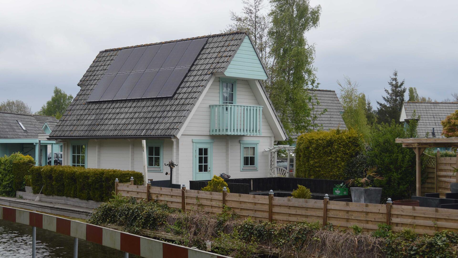 Huis in de Leine: witte muren, met een lichtblauwe gevel en een grijs dak met zonnepanelen.